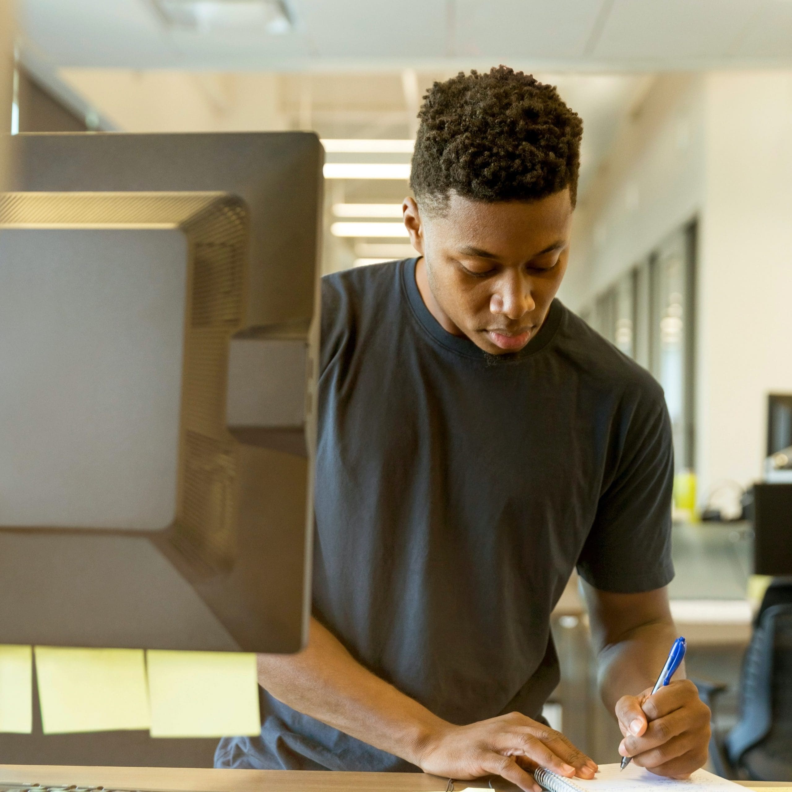 man writing by a computer