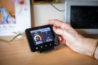 Older person’s hand holding a smart meter display